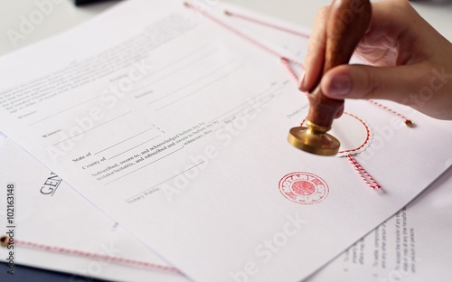 Close up on woman's notary public hand ink stamping the document