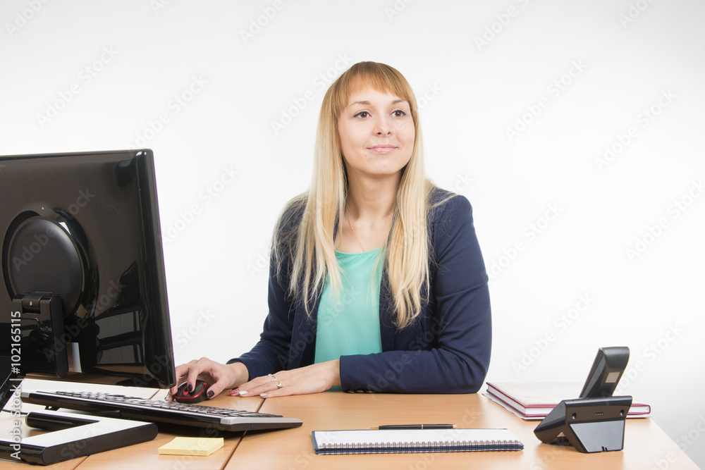 Beautiful girl secretary working at a computer looked at visitor