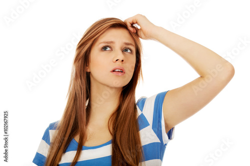 Pensive teenage woman scratching her head