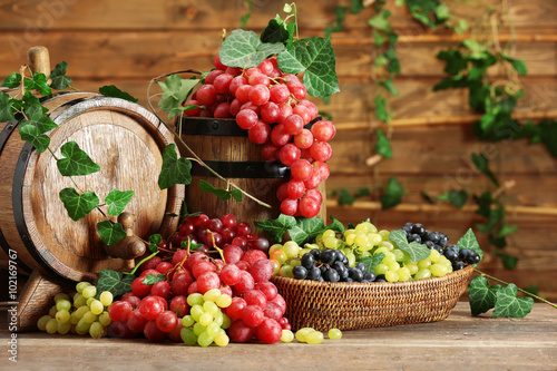 Grapes in bowl and barrel on wooden table