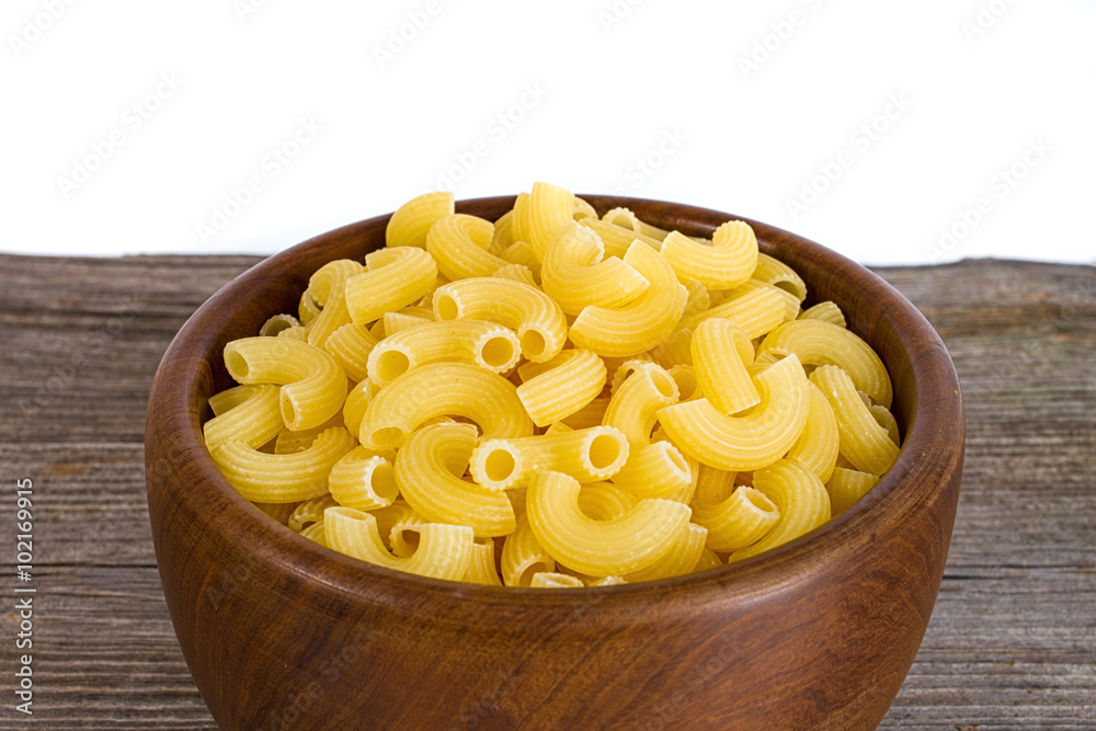 yellow raw pasta in wooden plate