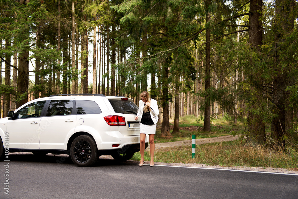 Young woman with broken car in the middle of forest