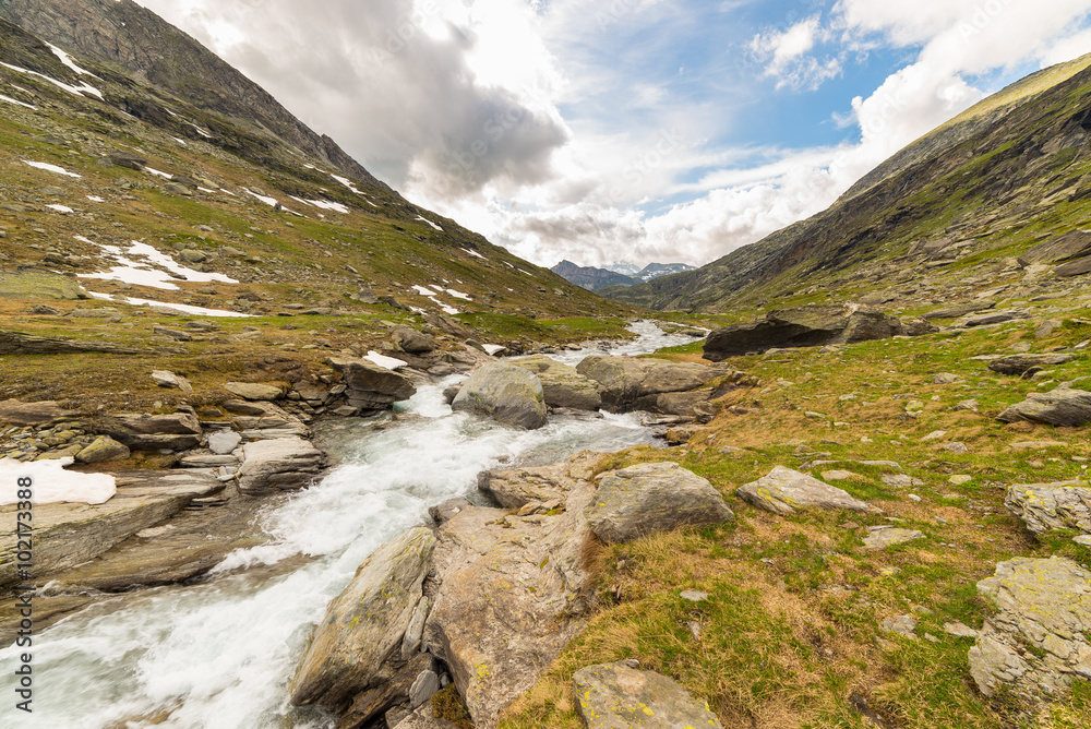 High altitude alpine stream with dramatic sky High altitude alpine stream with dramatic sky