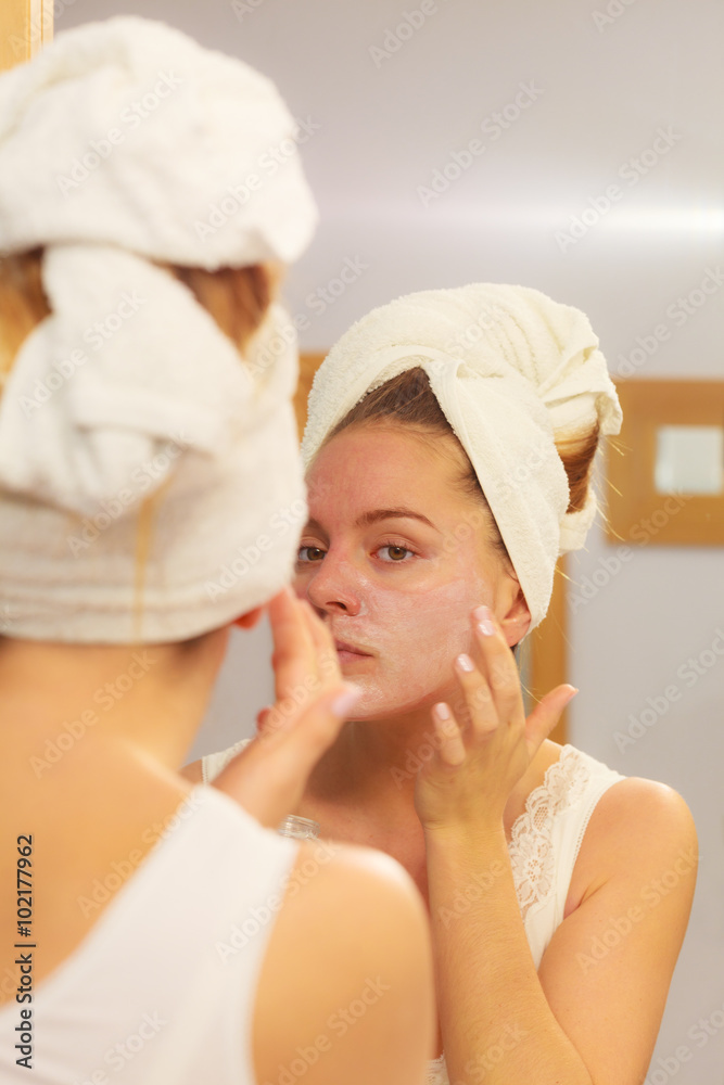 Woman applying mask cream on face in bathroom Woman applying mask cream on face in bathroom