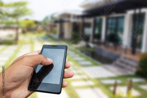 Hand hold and touch screen smart phone, tablet,cellphone over house or home for sale background, abstract background for solution of house or home or property.