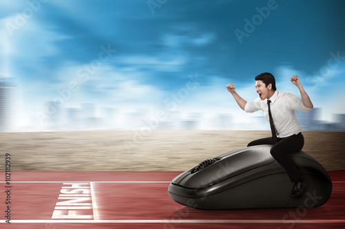 Asian business person riding computer mouse