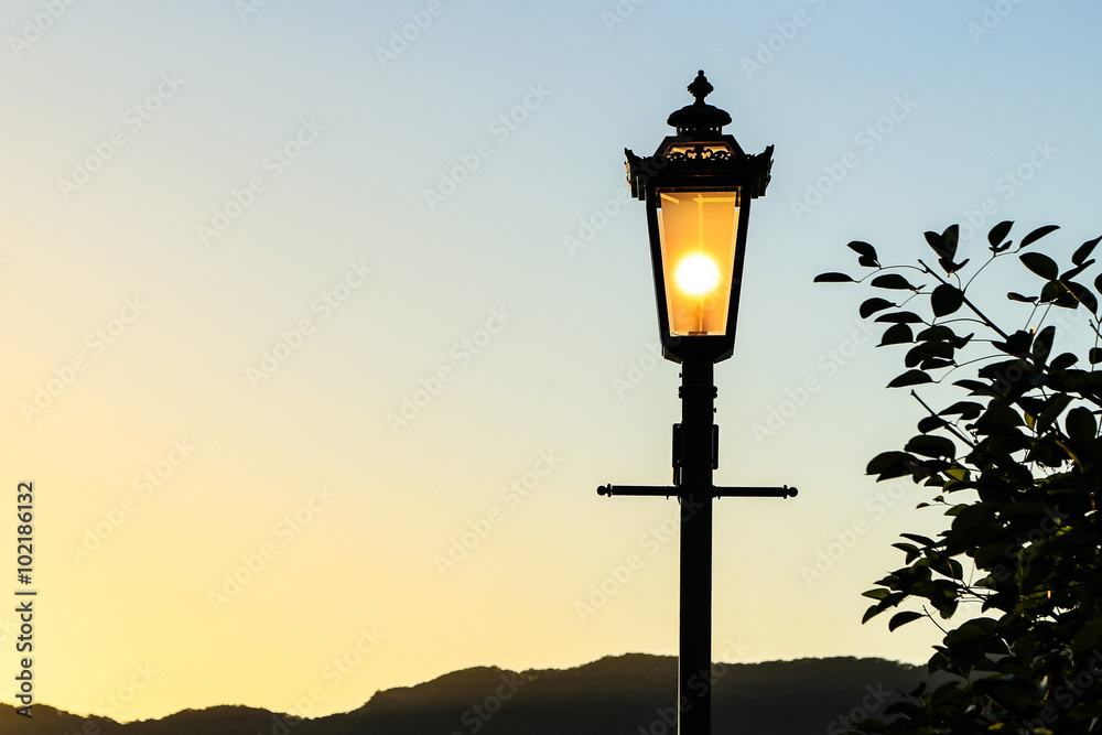 Vintage lamp post with sunset Background (sillhouette)