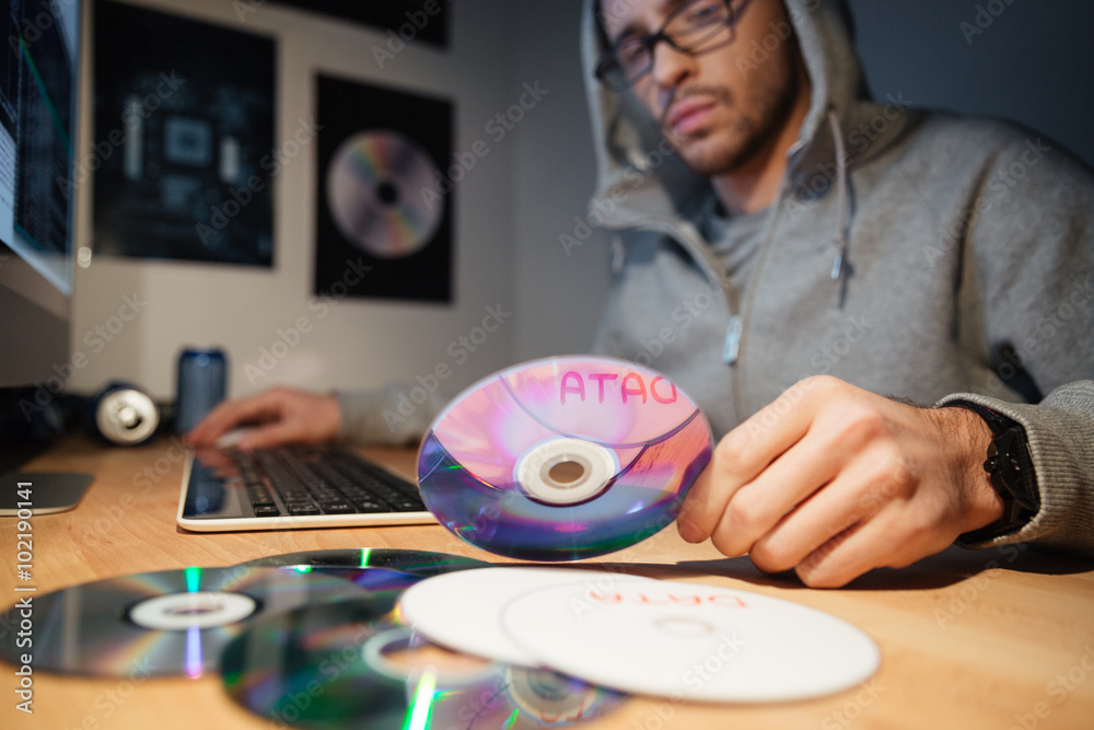 Thoughtful software developer in hoodie choosing CD with database