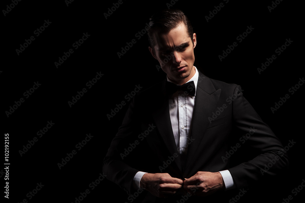 confident handsome man in black posing in dark studio confident handsome man in black posing in dark studio