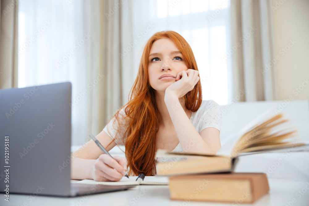 Thoughtful woman sitting at the table with her homework Thoughtful woman sitting at the table with her homework