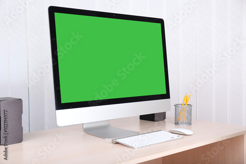 Modern computer with green screen, on table