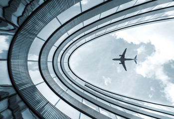 Low angle modern architecture building with landing airplane 