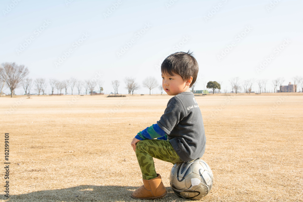 サッカーボールに座る男の子