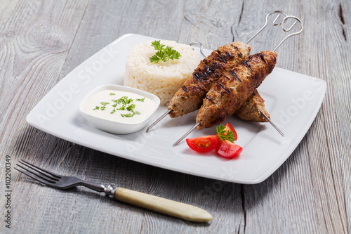 Barbecued kofta - kebeb with rice and vegetables on a plate. photo