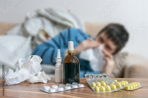 Pills in front of sick man who has flu or cold.