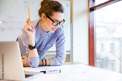 Happy woman working with blueprint near the window in office photo