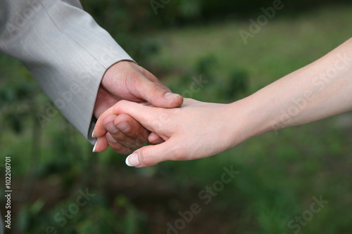 groom holds the bride by the hand closeup