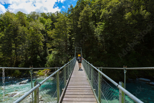 woman hiker with backpack walking on suspension bridge