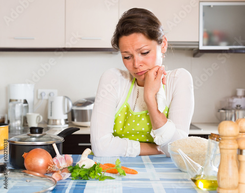 Sad woman cooking rice in the kitchen .