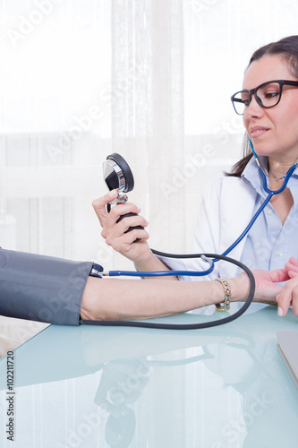 Young medic measuring patient blood pressure photo