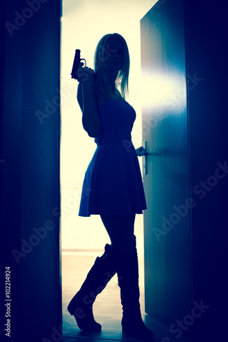 A woman wearing dress with gun In Doorway, backlight