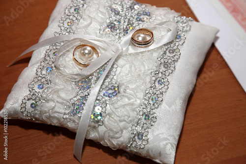 gold rings for wedding are on decorative pillow