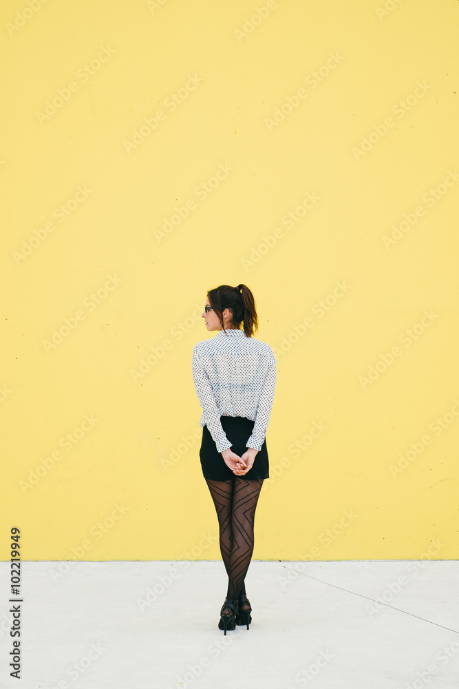 Professional modern business woman waiting outside against yellow wall. Professional modern business woman waiting outside against yellow wall.