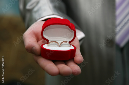 groom holds a box with gold wedding rings close up