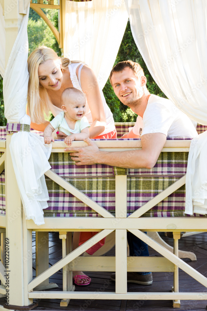 Obraz premium Happy young family spending time outdoors on a summer day with blue sky in background. Spending time together having fun and smiling. Parents and their child. 