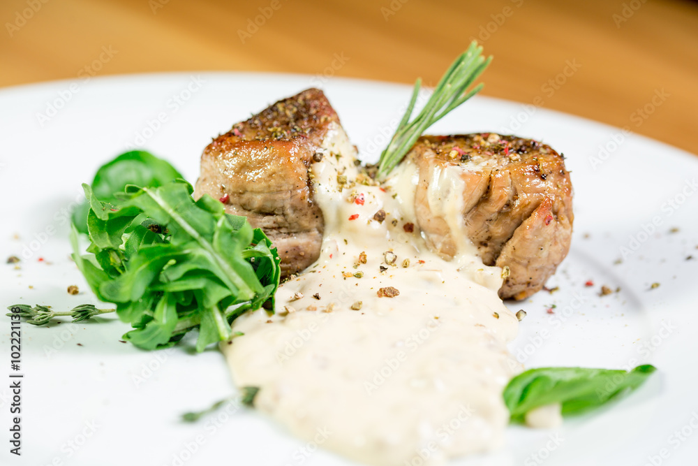 Beautiful juicy grilled meat with garnish on a wooden table Beautiful juicy grilled meat with garnish on a wooden table