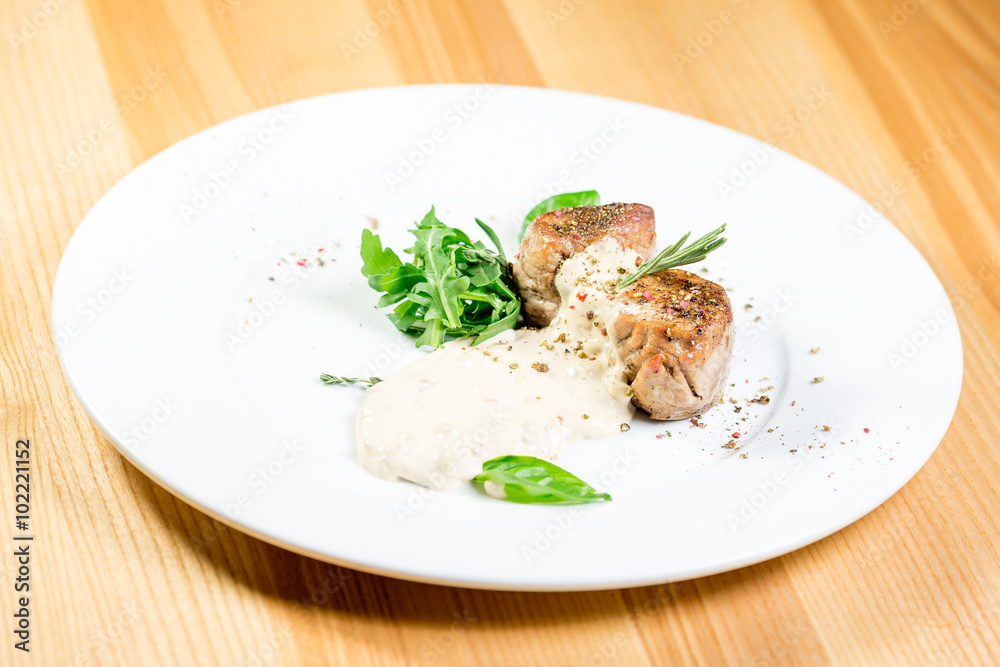 Beautiful juicy grilled meat with garnish on a wooden table Beautiful juicy grilled meat with garnish on a wooden table