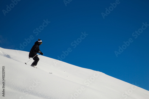 Male skier skiing in fresh snow on ski slope on a sunny winter day at the ski resort in Georgia
