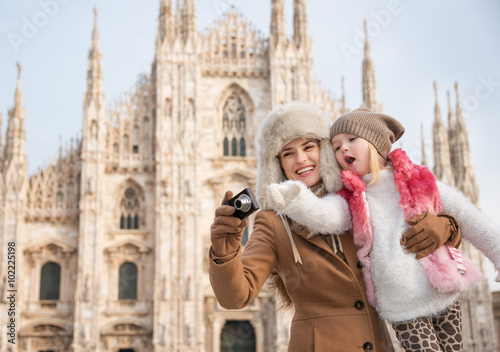 Happy mother and daughter taking photos in front of Duomo, Milan