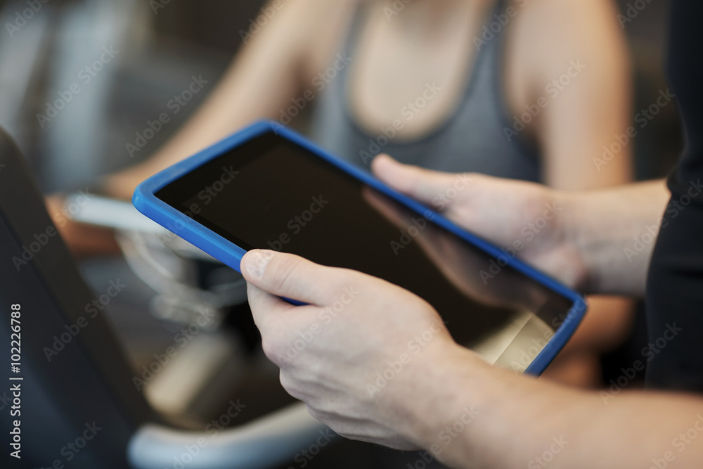 Fototapeta premium close up of trainer hands with tablet pc in gym