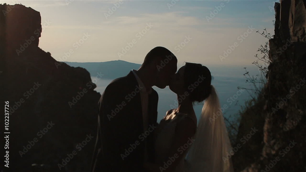 Married couple, bride and groom, kissing on mountain volcano landcape in Santorini, Greece close up