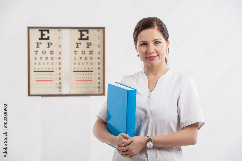 Doctor optometrist with blue book and eye chart in the backgroun Doctor optometrist with blue book and eye chart in the backgroun