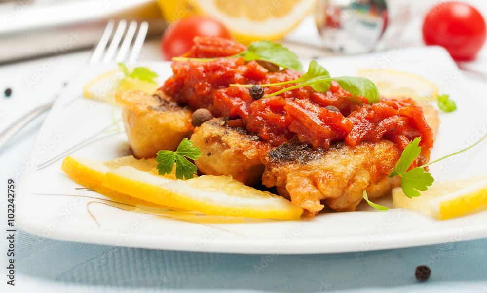 Pieces of fried fish in tomato sauce with carrots.