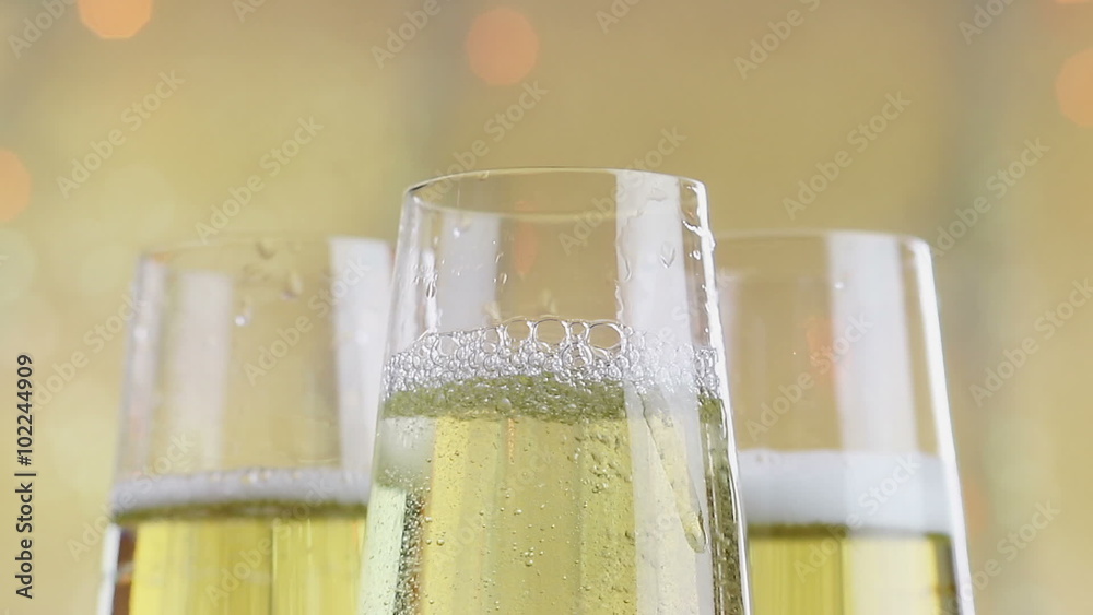 filling flutes of champagne with golden bubbles against gold bokeh background, holiday concept zoom out movement camera