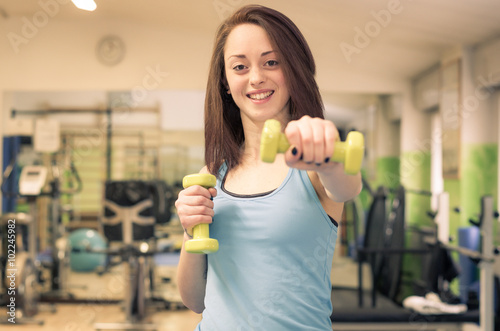 Beautiful caucasian girl is training in the gym lifting weights - concept about people and sport