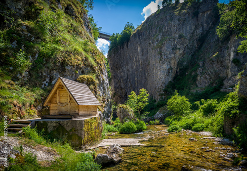 Nevidio canyon. Rock cliff, river, bridge and small wooden house. Invisible canyon, popular touristic attraction of Montenegro.