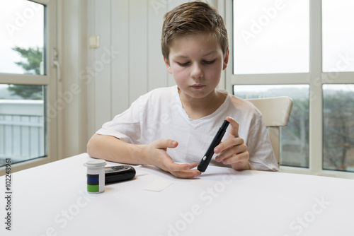 Boy measure glucose or blood suger level photo