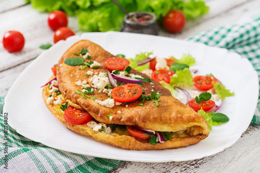 Omelet with tomatoes, parsley and feta cheese on white plate. Omelet with tomatoes, parsley and feta cheese on white plate.