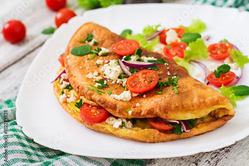 Omelet with tomatoes, parsley and feta cheese on white plate.