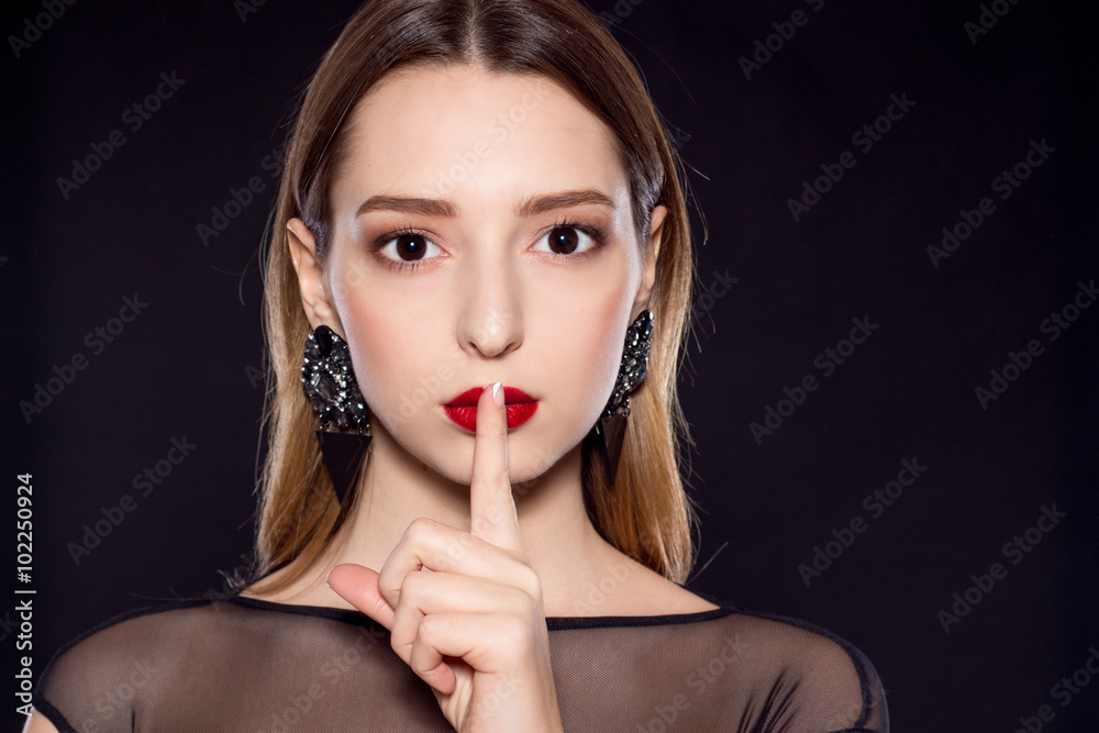 Portrait of a beautiful young woman on a black background. Beautiful woman with red lips in black dress. Portrait of a beautiful young woman on a black background. Beautiful woman with red lips in black dress.