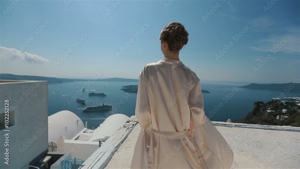 Beautiful sexy brunette bride in robe moving on the roof with sea and mountains in background