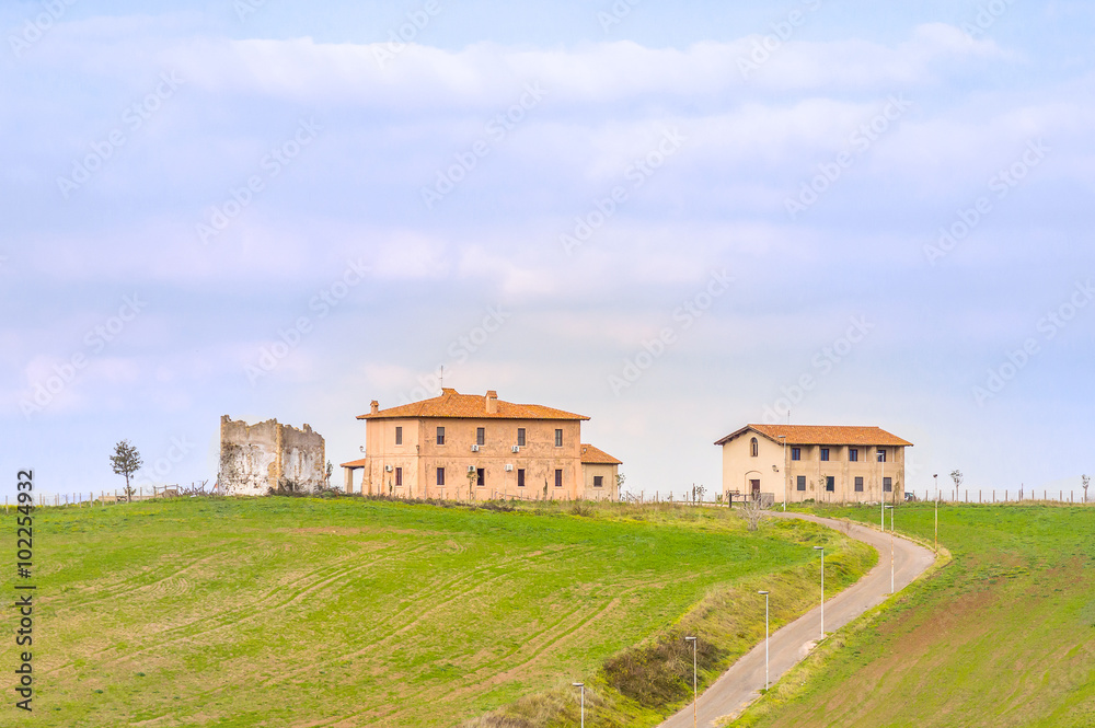 Two old rural countryside Mediterranean houses on a meadow hill with a road