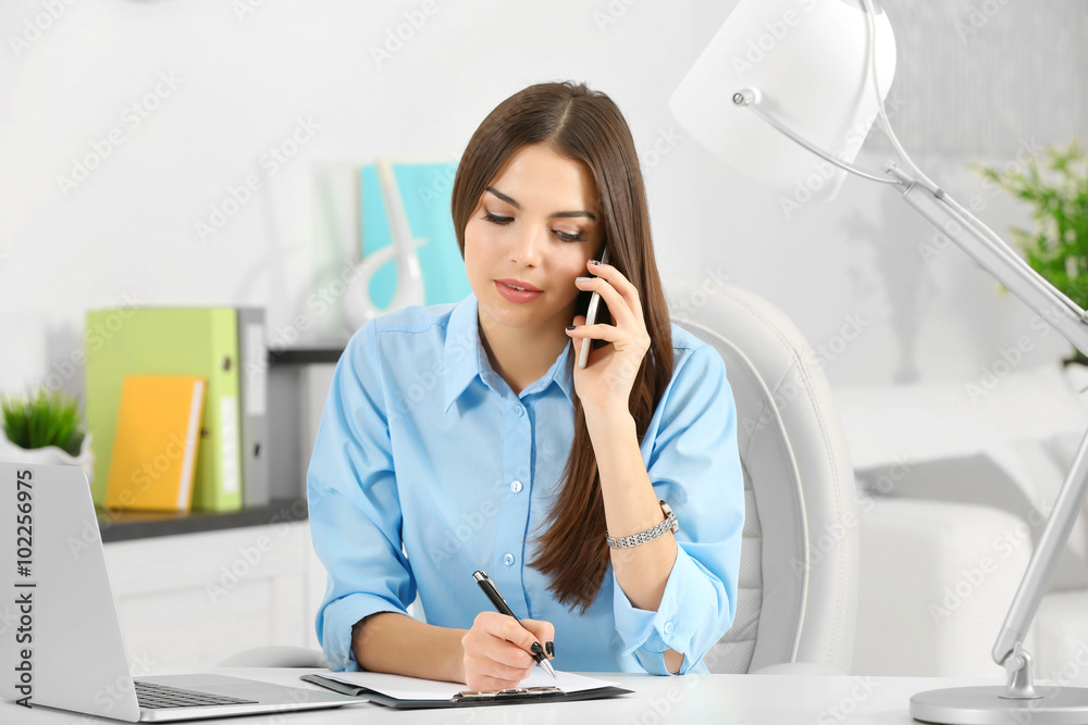 A beautiful successful woman talking on phone at the modern office A beautiful successful woman talking on phone at the modern office