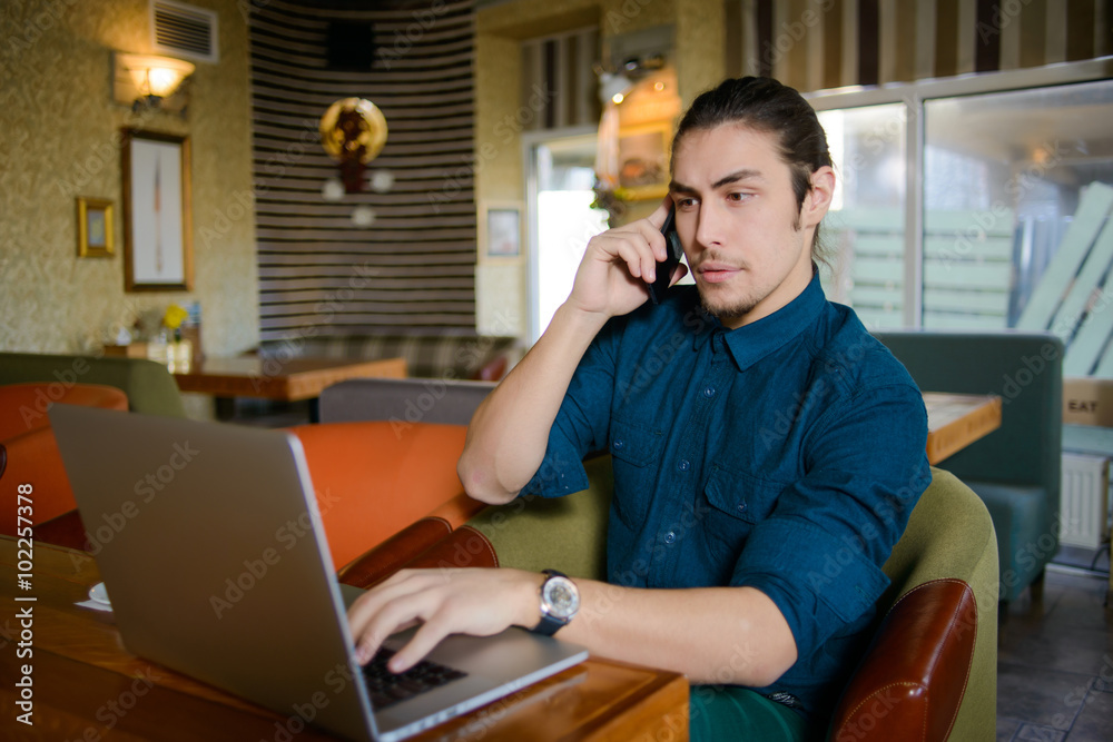 Young man drinking coffee and working on laptop in a cafe