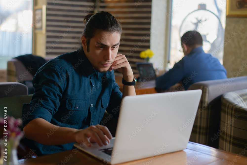 Young man drinking coffee and working on laptop in a cafe