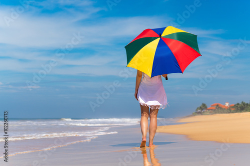 Girl with an colorful umbrella on the sandy beach